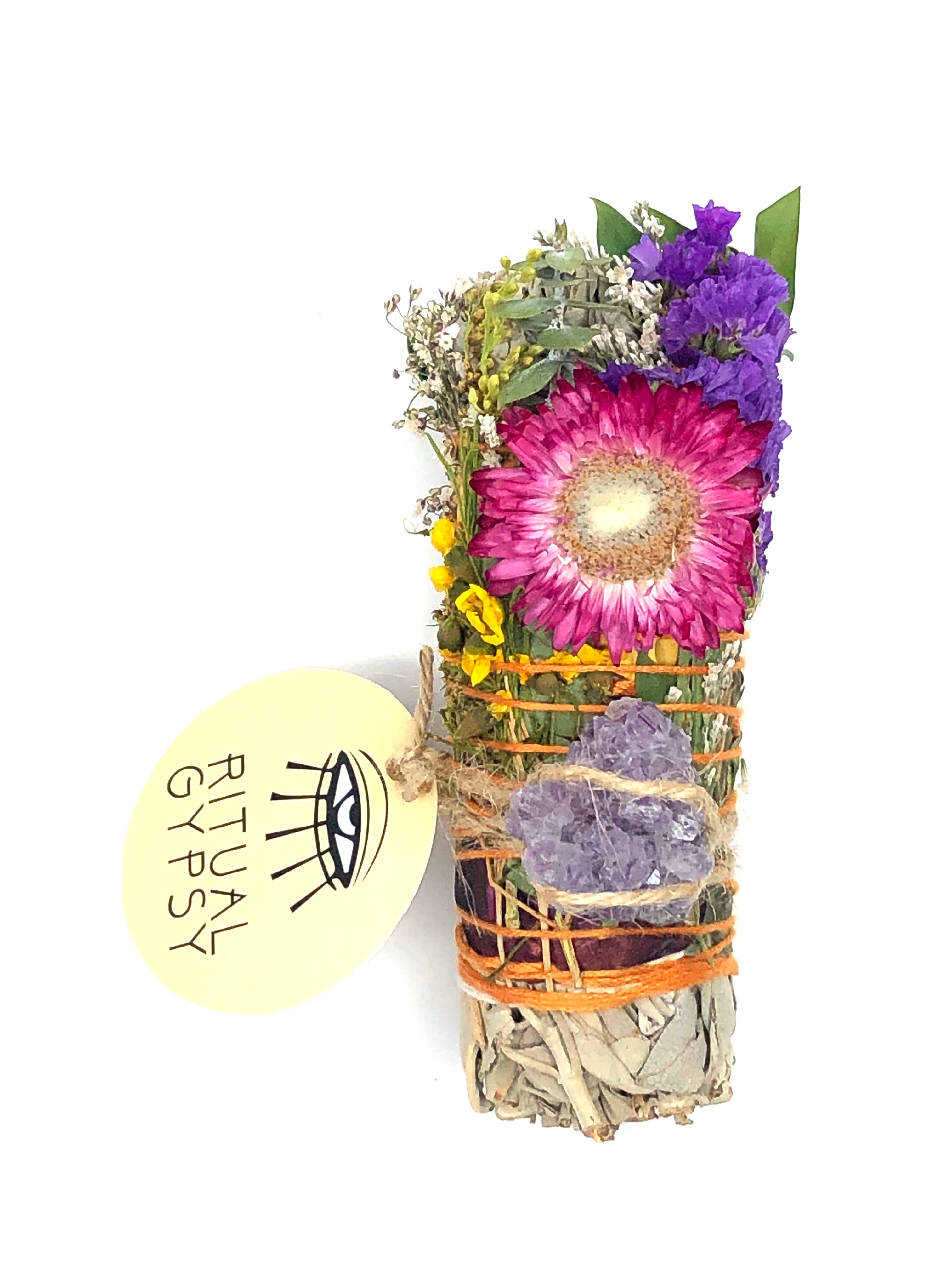 4" small white sage smoke cleansing smudge bundles with pink and purple statice and pink strawflower wrapped in florals with amethyst crystal and round product tag saying ritual gypsy attached