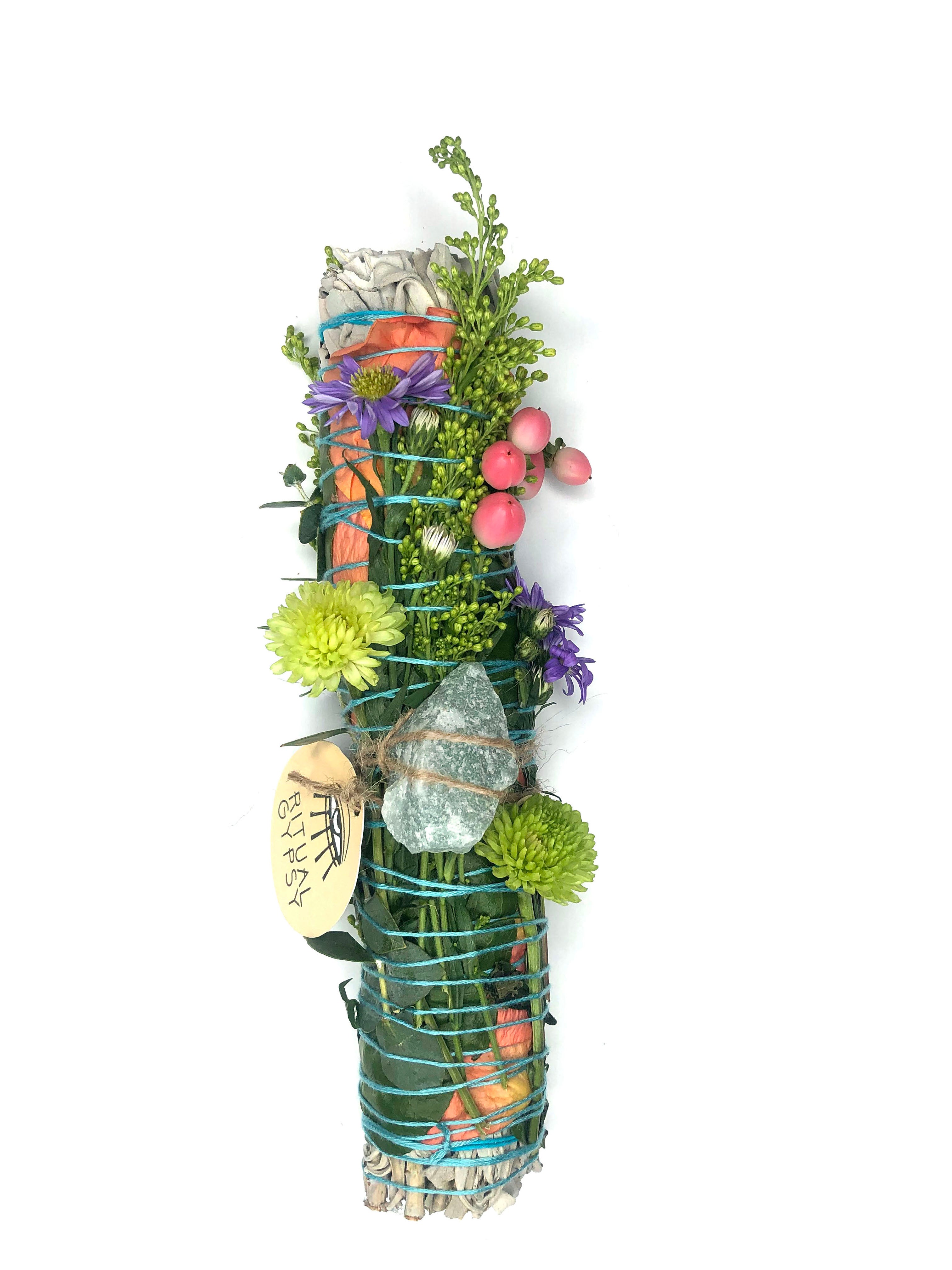 white sage smoke cleansing smudge bundle wrapped in florals with orange red strawflower and green aventurine crystal and round ritual gypsy product tag attached on white background