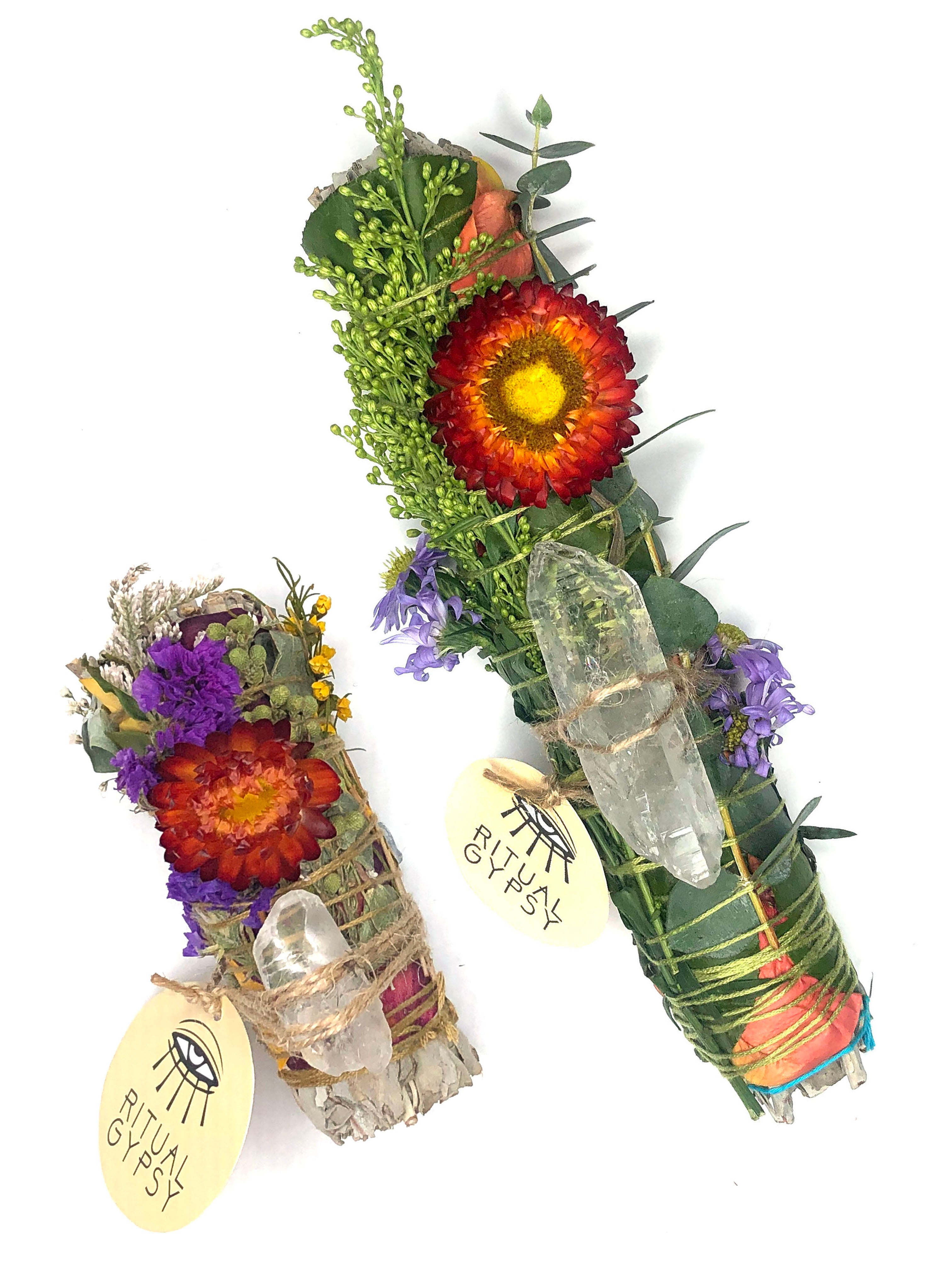 4" small white sage smoke cleansing smudge bundles with pink and purple statice and pink strawflower wrapped in florals with clear quartz crystal and round product tag saying ritual gypsy attached