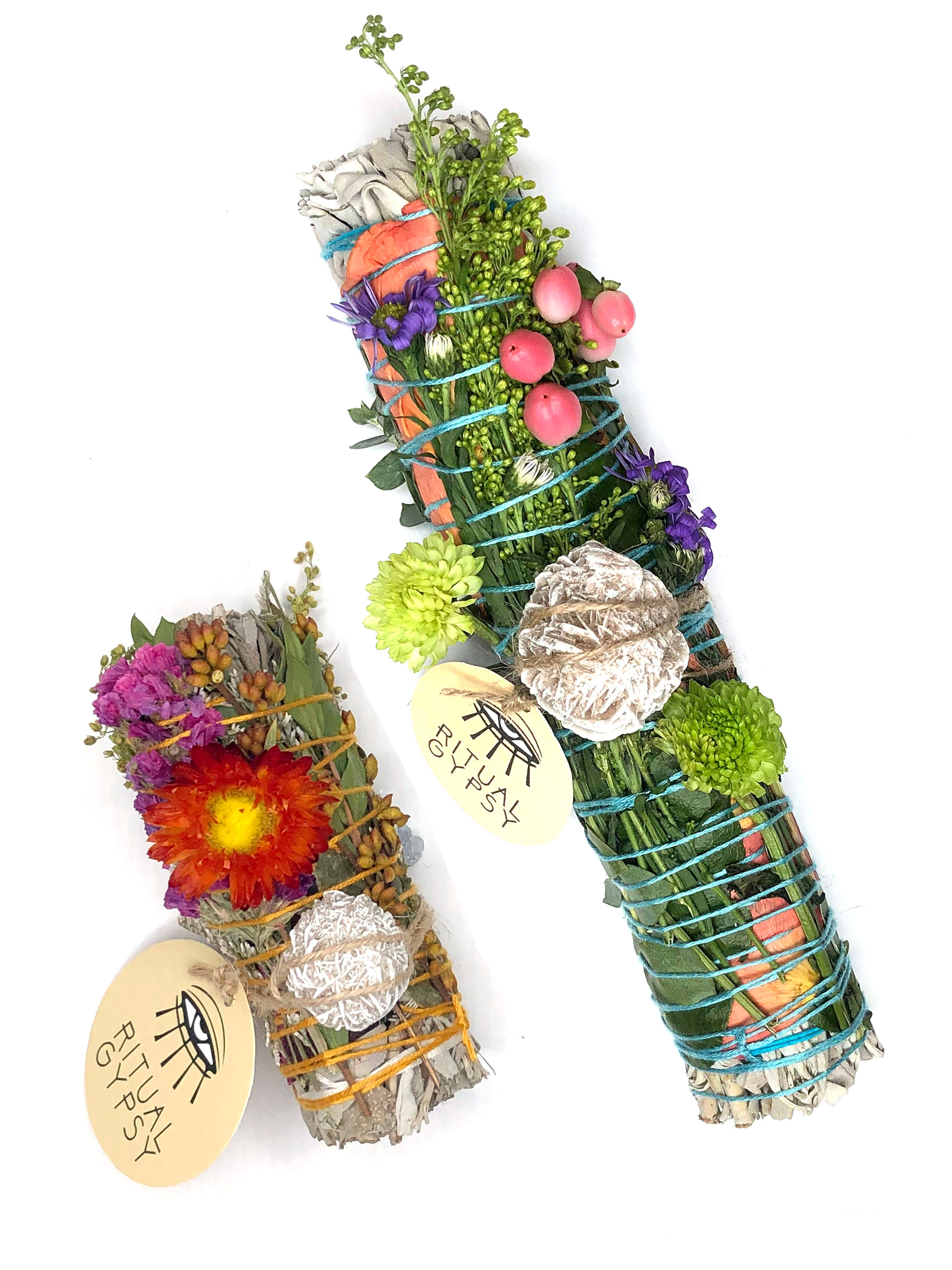 white sage smoke cleansing smudge bundle wrapped in rose petals, red straw flower and florals with white round desert rose crystal and round ritual gypsy product tag on white background