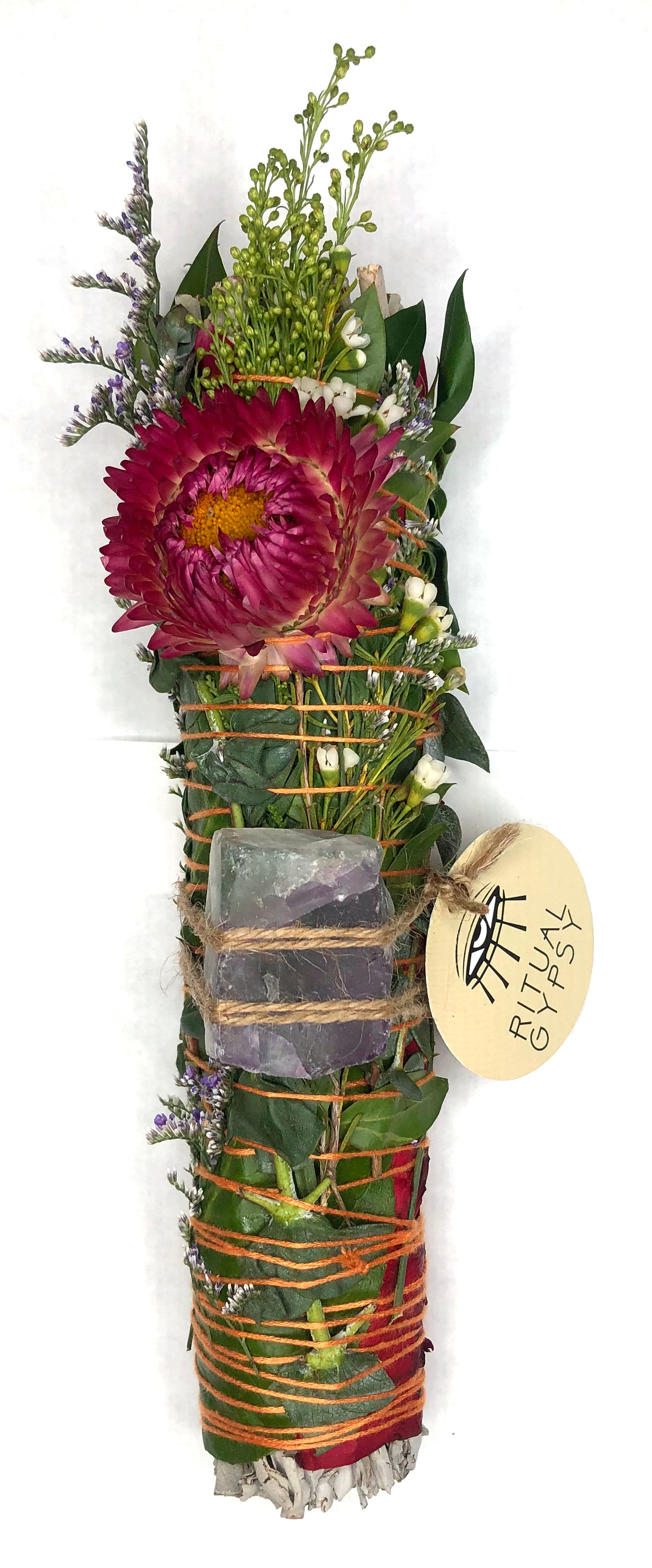 white sage smoke cleansing smudge bundle wrapped in florals with orange red strawflower and blue purple green fluorite crystal and round ritual gypsy product tag attached on white background