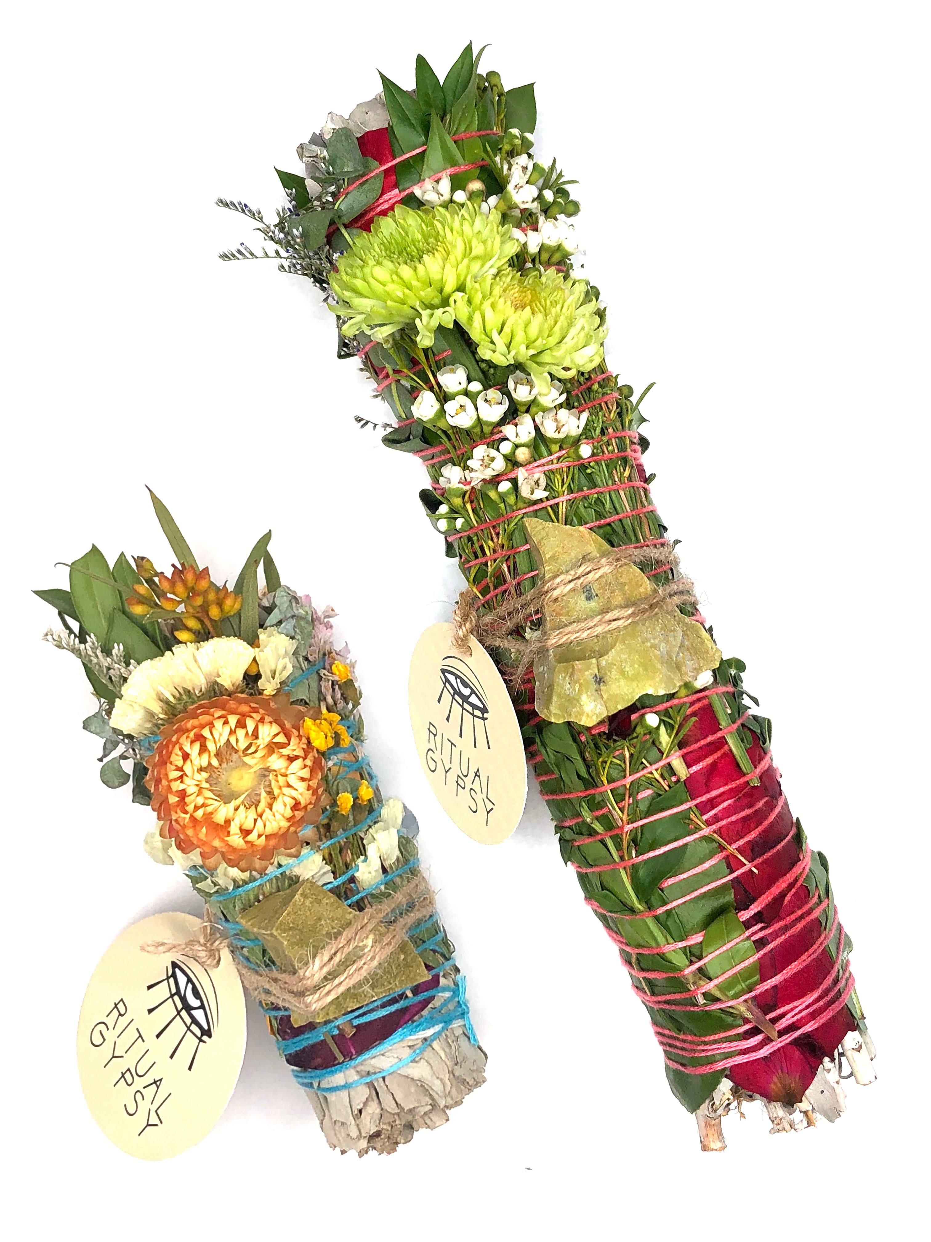 white sage smoke cleansing smudge bundle wrapped in florals with orange strawflower and green opal crystal and round ritual gypsy product tag attached on white background