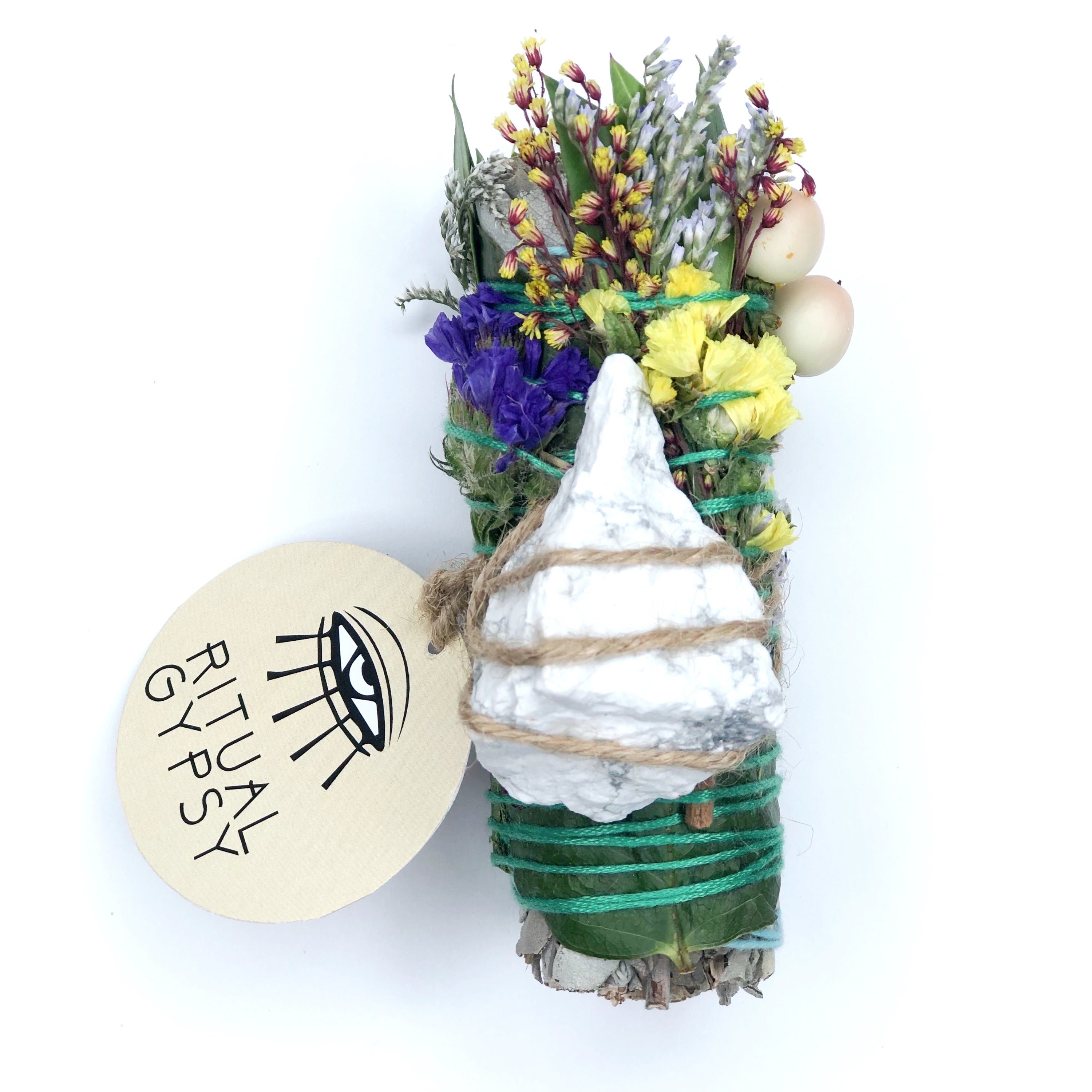 white sage smoke cleansing smudge bundle wrapped in florals and white howlite crystal stone and round ritual gypsy product tag attached on white background