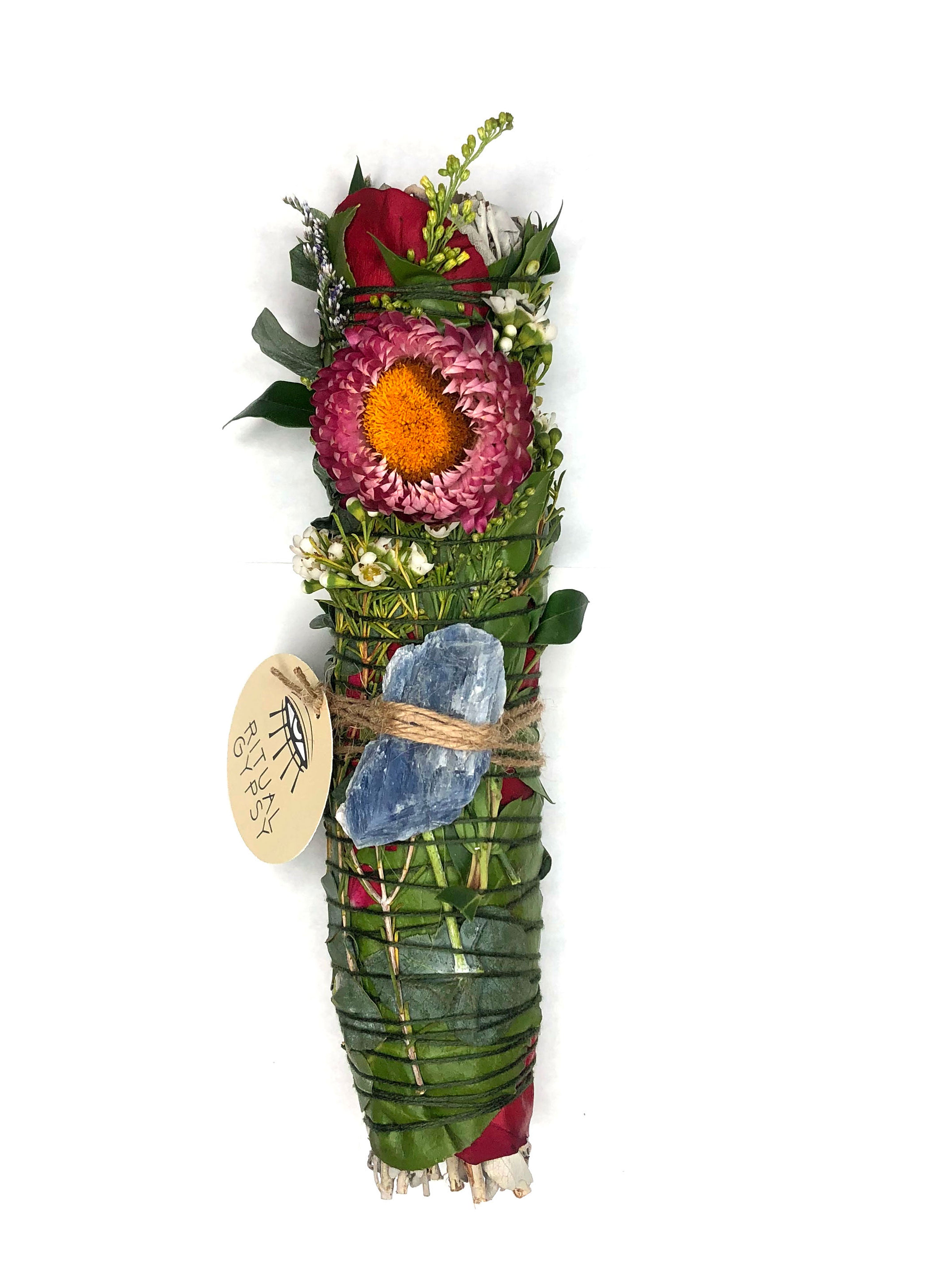 white sage smoke cleansing smudge bundle wrapped in florals with red strawflower and blue kyanite blade crystal and round ritual gypsy product tag attached on white background