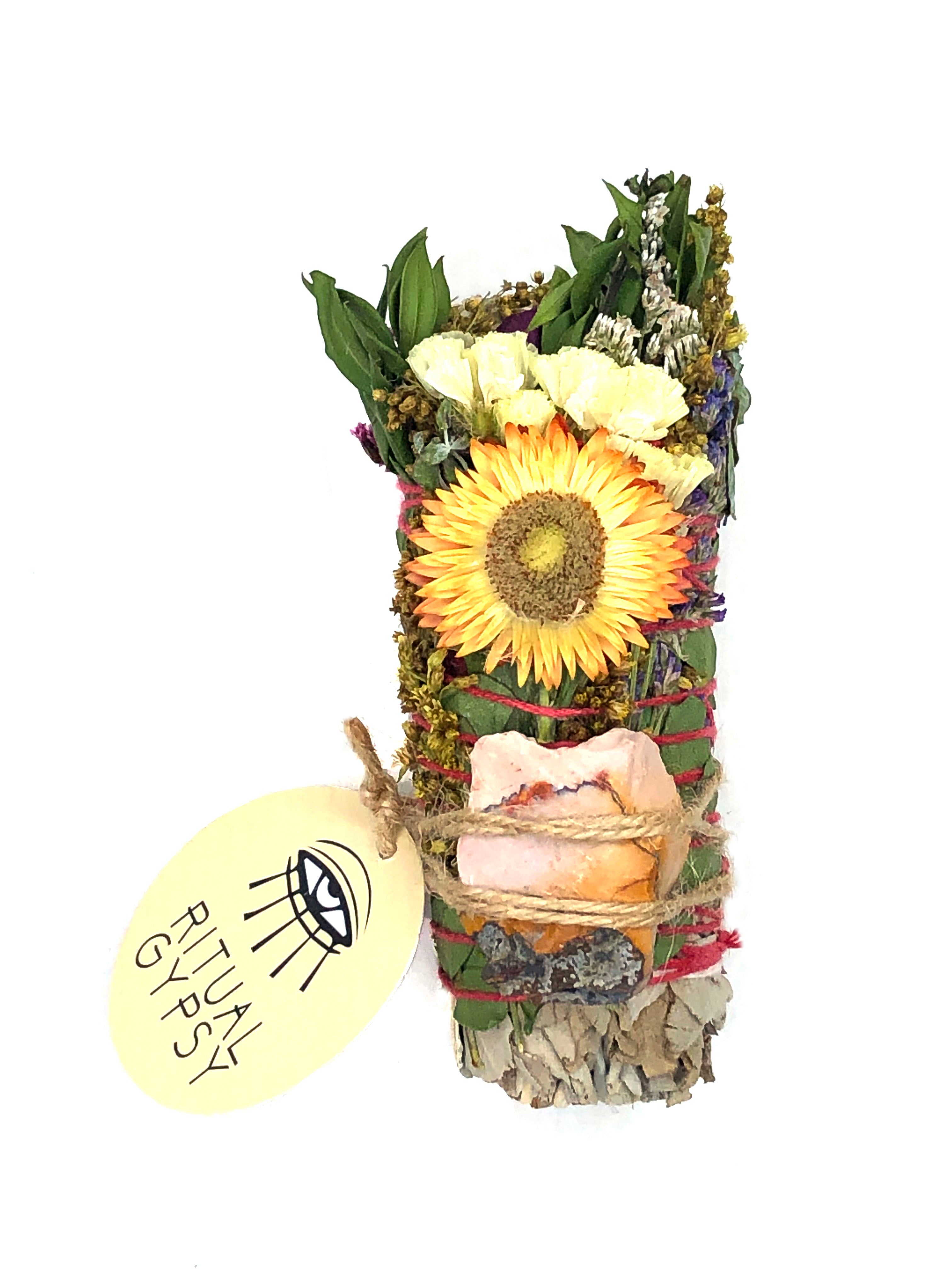 white sage smoke cleansing smudge bundle wrapped in florals with orange yellow strawflower and orange pink mookaite crystal stone and round ritual gypsy product tag attached on white background