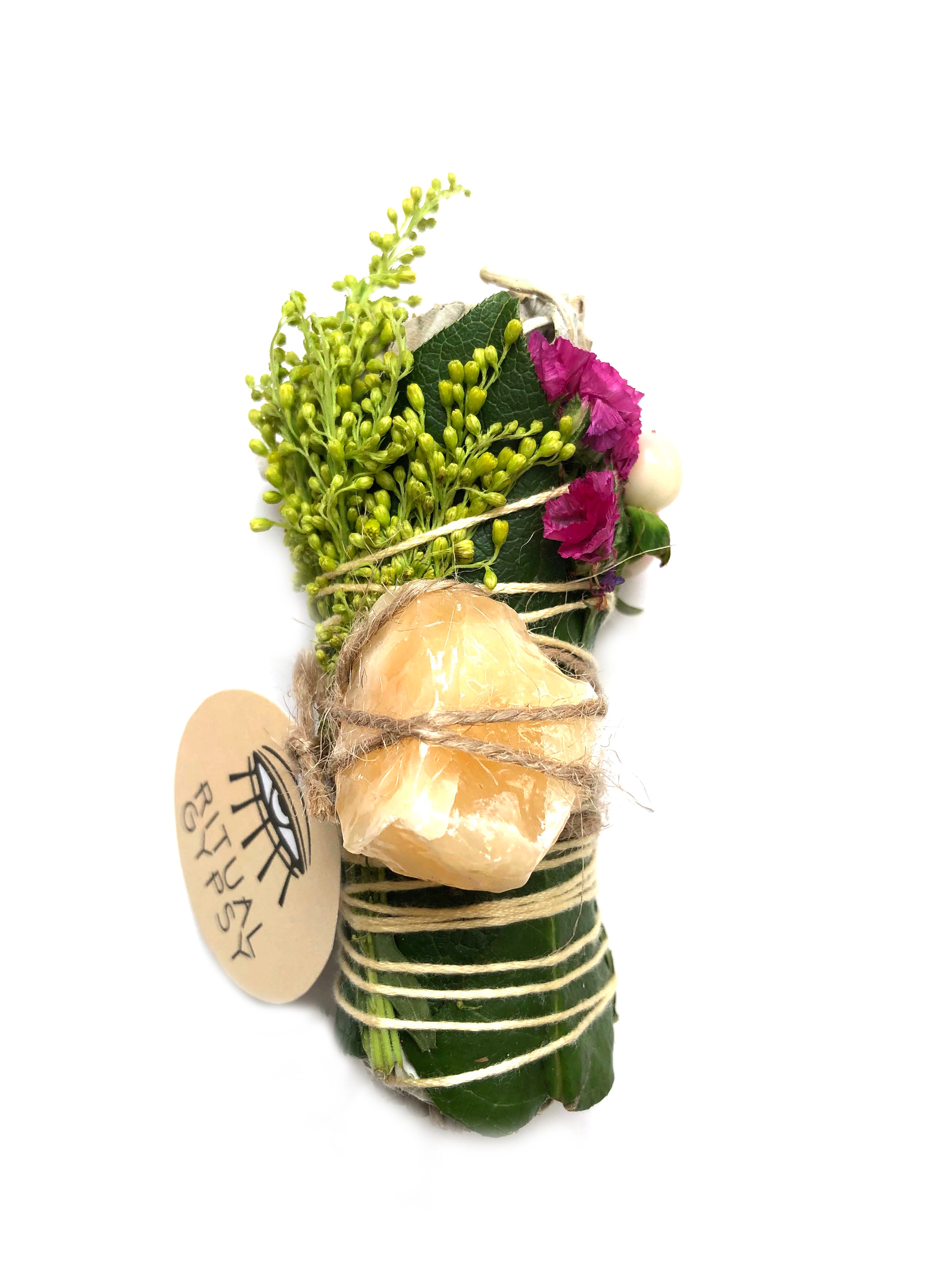 white sage smoke cleansing smudge bundle wrapped in florals with pink strawflower and orange calcite crystal stone and round ritual gypsy product tag attached on white background