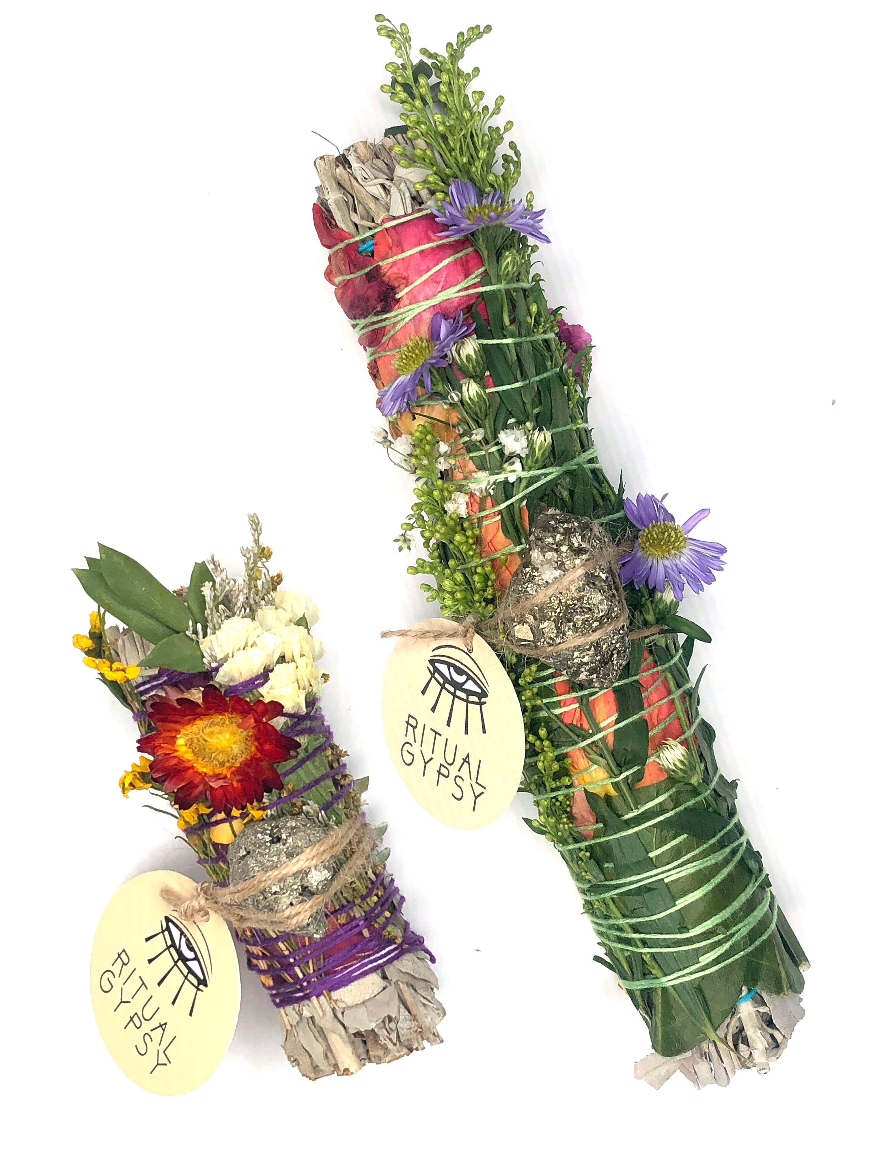 white sage smoke cleansing smudge bundle with pink and white statice and red strawflower wrapped in florals with white gold pyrite crystal and round ritual gypsy product tag