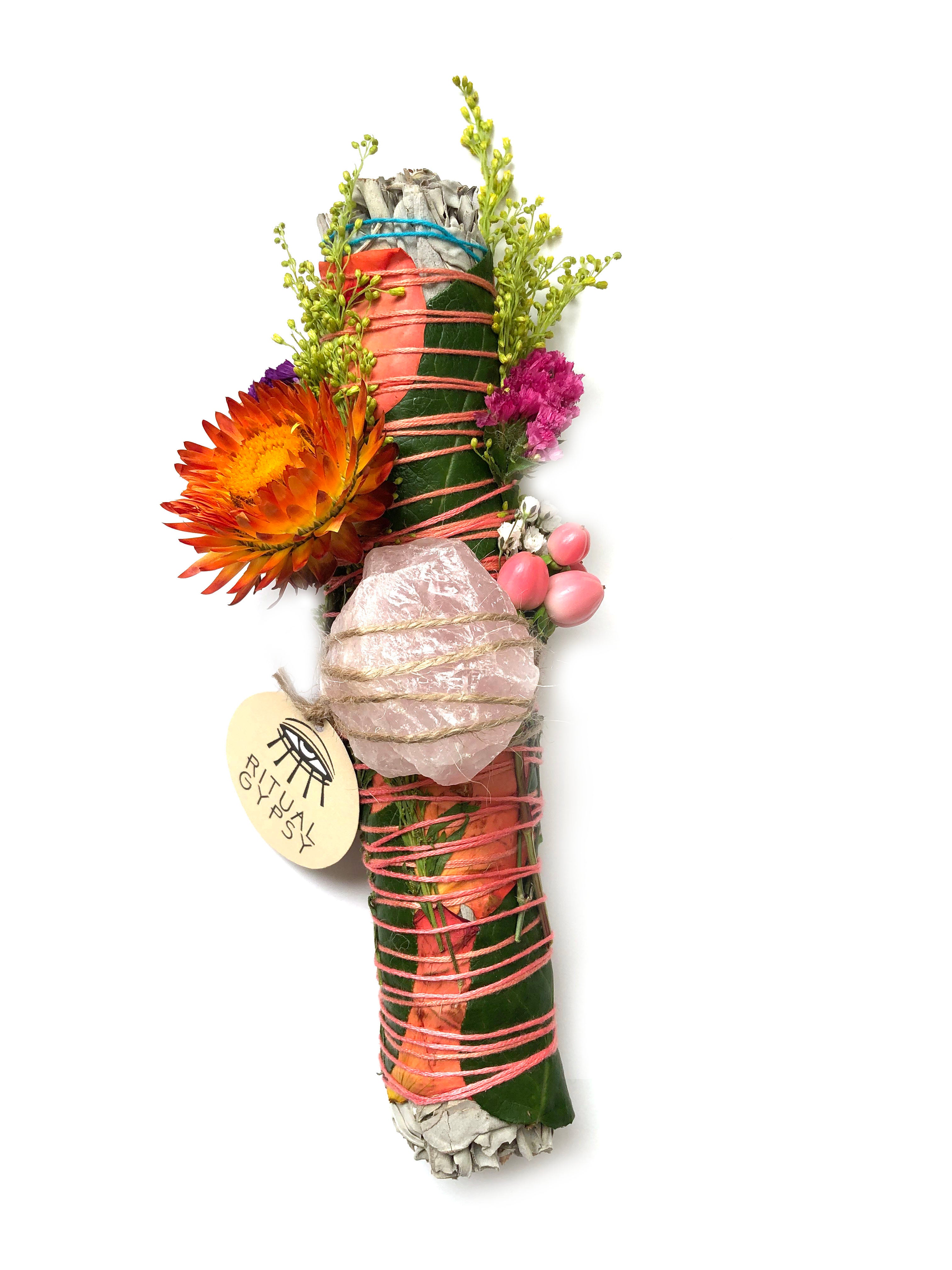 small white sage smoke cleansing smudge bundle with pink statice and pink strawflower wrapped in florals with rose quartz and round product tag saying ritual gypsy attached