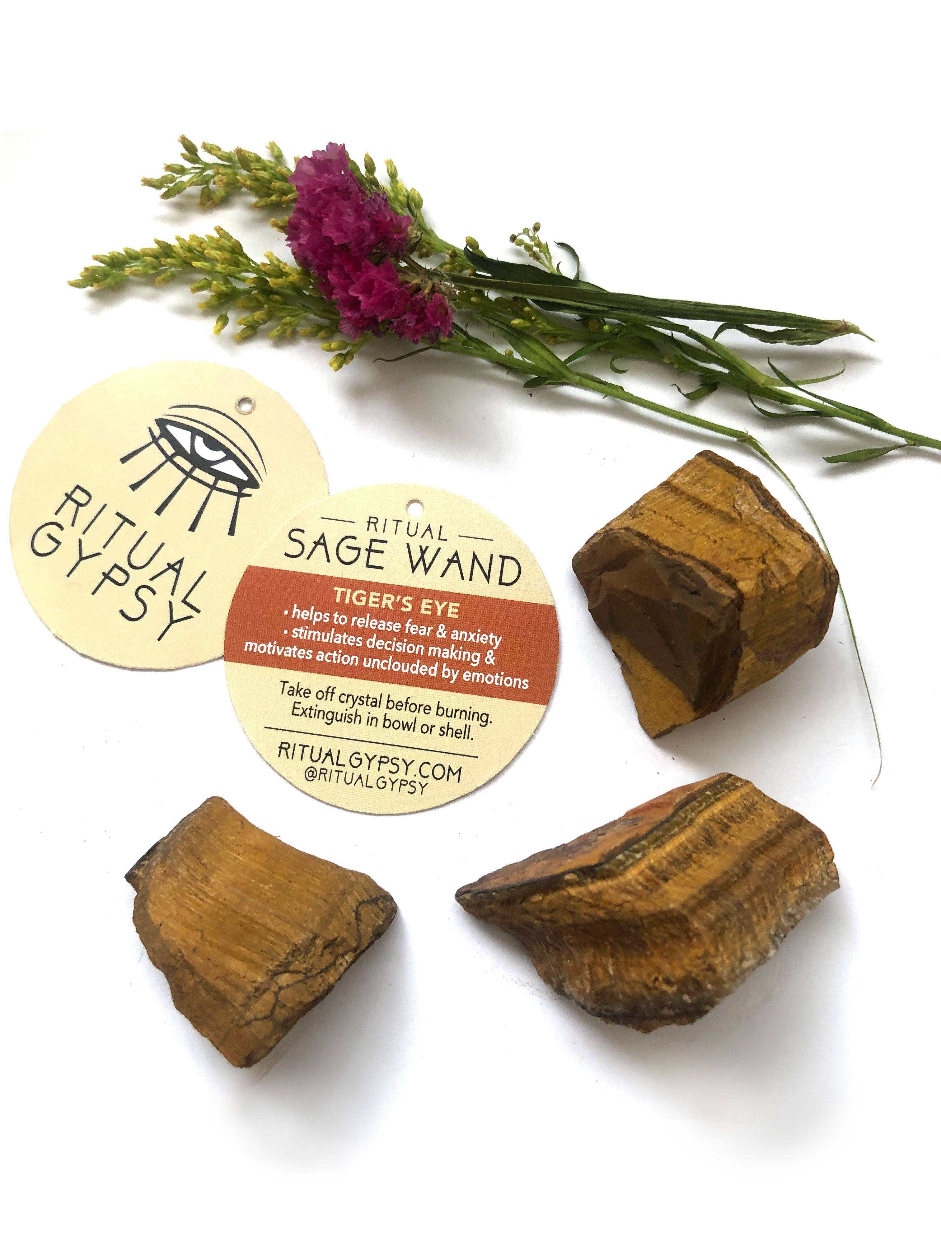 3 brown orange tan tiger's eye crystals and round ritual gypsy product tags on white surface